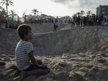 Palestinians look at the destruction after an Israeli airstrike on a crowded tent camp hou