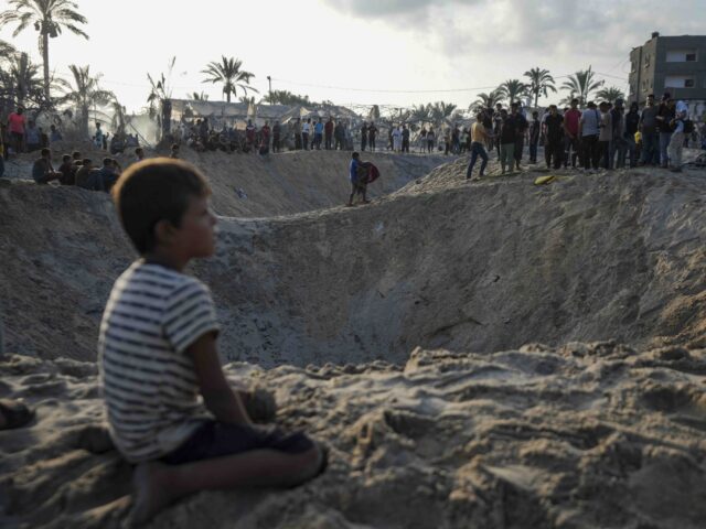 Palestinians look at the destruction after an Israeli airstrike on a crowded tent camp hou