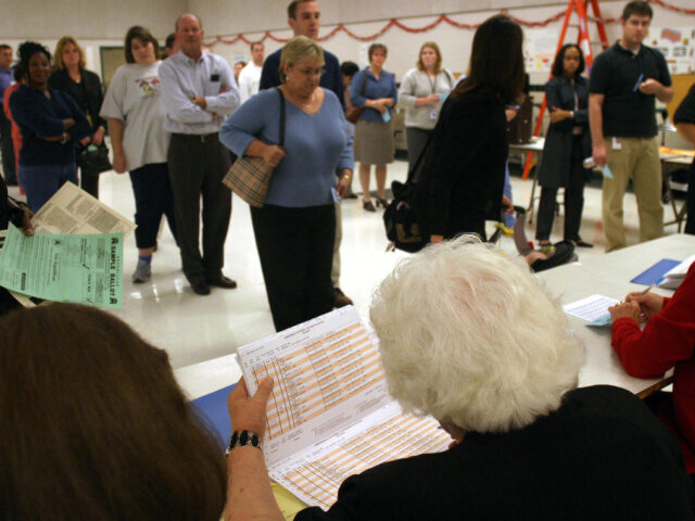 Election Officer Miriam Godfrey (white hair,back to camera) checking voter rolls at the Gr