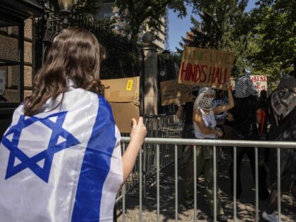 A pro-Israel student holds a sign while pro-Palestinian supporter hold picket line outside