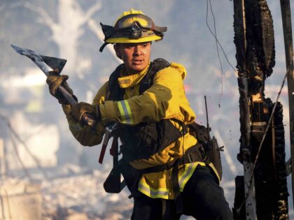 Firefighter Jonathan Lievanos extinguishes hot spots at a home destroyed by the Boyles fir