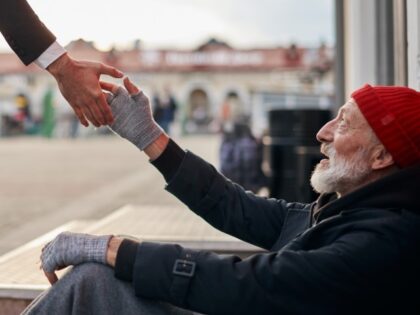 Senior beggar sitting beside street with request help with receive some coins from kind bu