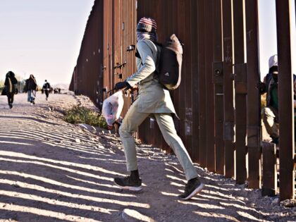 Migrants cross through a cut in the US-Mexico border fence in Lukeville, Arizona, US, on T