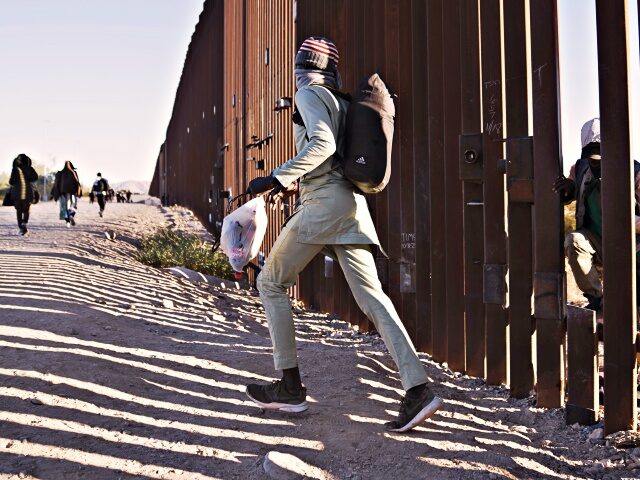 Migrants cross through a cut in the US-Mexico border fence in Lukeville, Arizona, US, on T