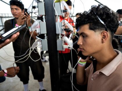 Alex Espinoza, 20, from Venezuela talks on his phone as he waits for a bus to New York Cit