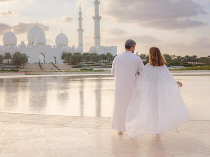 Arab couple visiting park near Grand Mosque in Abu Dhabi wearing traditional dress.