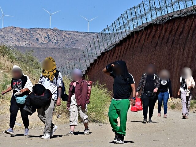 Migrants walk on the US side of the border wall in Jacumba Hot Springs, California on June