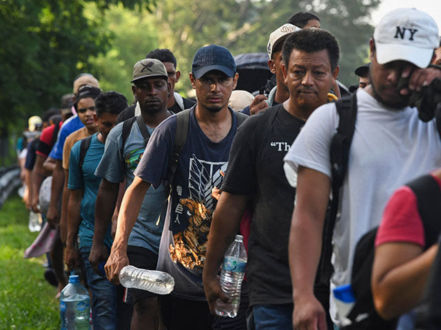 Migrants, mostly from Central America and Venezuela, walk towards the United States on the