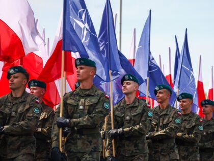 Soldiers carry flags of NATO and flags of the Republic of Poland during a military parade