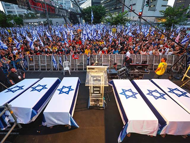 Protesters lift flags and placards next to symbolic coffins representing six Israeli hosta