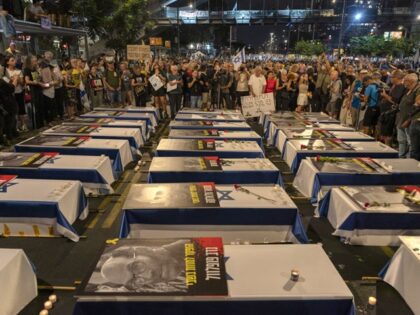 Protesters in front of coffins draped Israeli flag with during a demonstration urging the