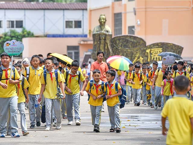 Primary school students walk home as the school suspends classes to brace for Typhoon Yagi