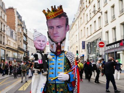 TOPSHOT - A protestor wearing a mask with the face of France's President Emmanuel Macron h