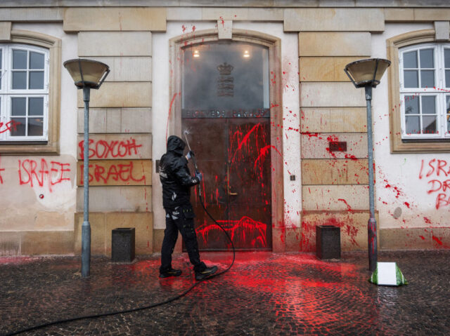 A worker uses a pressure hose to clean the red paint and anti Israel slogans from the faca