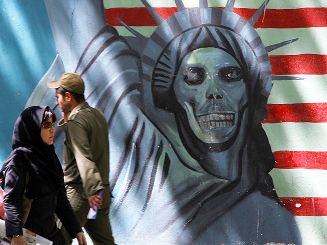 Iranians walk past an anti-US mural painting depicting the Statue of Liberty on the wall o