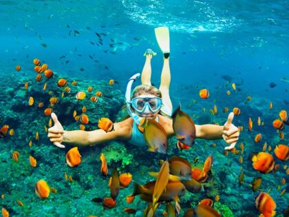 Young woman snorkeling with coral reef fishes