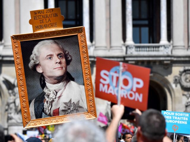 A protester holds a portrait of French President Emmanuel Macron as Louis XVI with the let