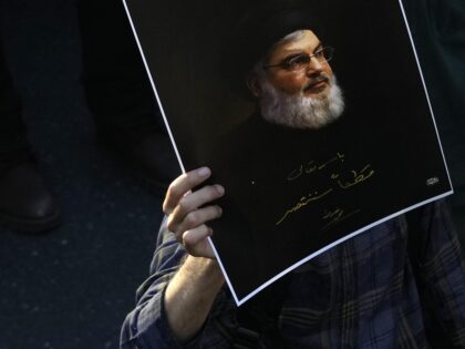 A mourner holds up a poster of slain Hezbollah leader Hassan Nasrallah with a quotation of