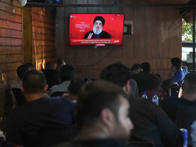 People watch the speech of Hezbollah leader Hassan Nasrallah on a tv screen as they sit in