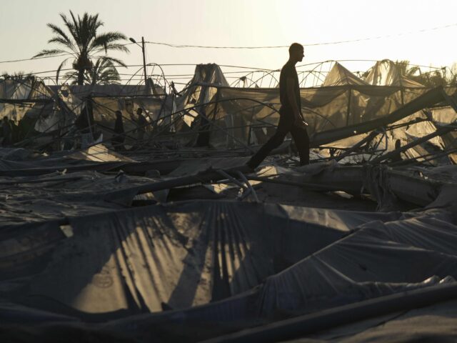 Palestinians look at the destruction after an Israeli airstrike on a crowded tent camp hou