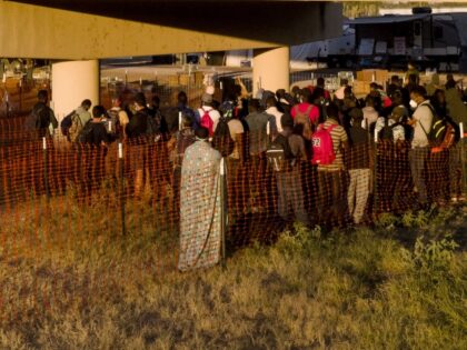 Migrants, many from Haiti, wait in lines to board buses under the Del Rio International Br