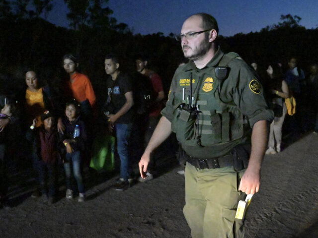 An US Border Control Fedaral Agent patrols as a group of asylum-seeker line up after arriv