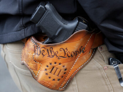 An attendee at a gun rights rally open-carries his gun in a holster that reads "We th