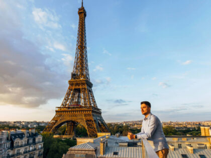 Young man looking at the sunset from the balcony with Eiffel Tower in the background, Pari