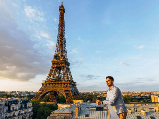 Young man looking at the sunset from the balcony with Eiffel Tower in the background, Pari