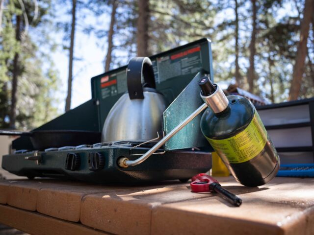 low angle view of a one pound (16 oz) propane tank, attached to a portable stove, with a f