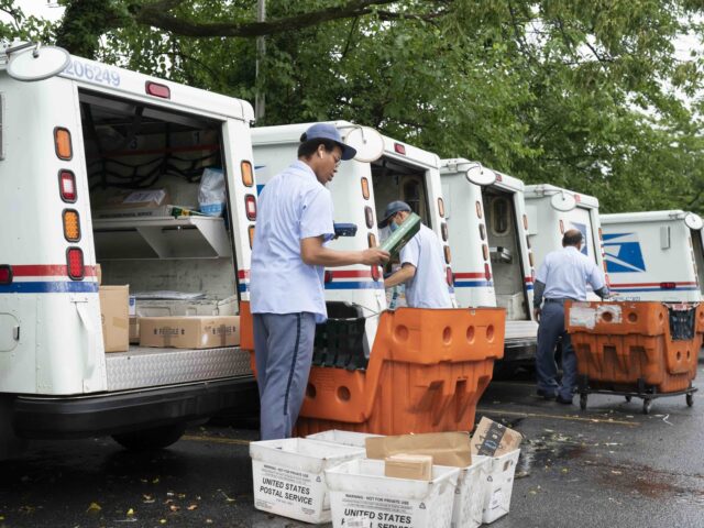 FILE - In this July 31, 2020, file photo, letter carriers load mail trucks for deliveries