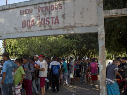 Venezuelan refugees wait in a line to get food from volunteers at the Simon Bolivar square