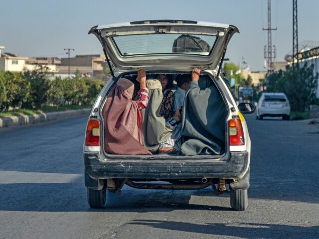 Afghan burqa-clad women travel on the back of a local taxi in Kandahar on September 9, 202