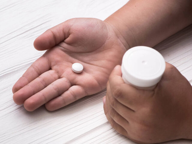 Child hand with white medical pills - stock photo