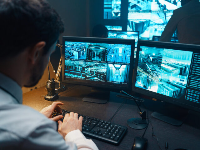 Security guard watching video monitoring surveillance security system. - stock photo