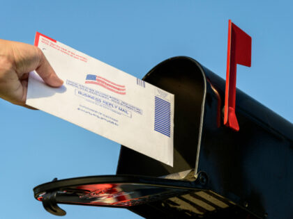 Woman's hand placing a 2020 mail-in election ballot in a rural mailbox - stock photo