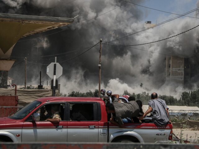 Palestinians on a vehicle pass a bomb blast during an Israeli airstrike on the Ain Jalut t