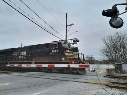 a train traveling down train tracks next to a traffic light and railroad crossing