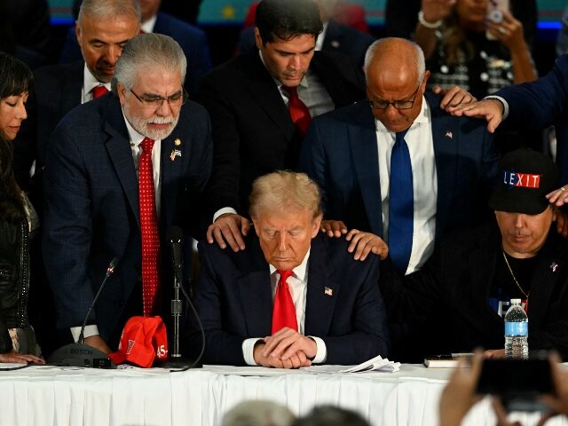 Former US President and Republican presidential candidate Donald Trump prays during a roun