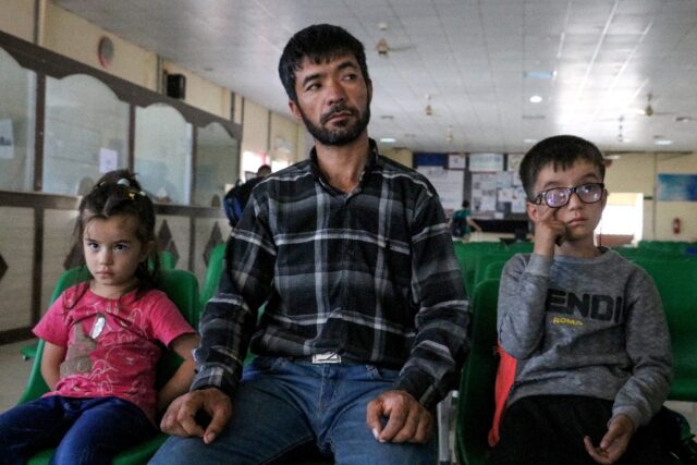 An Afghan refugee sits with his children after their deportation from Iran, at a registrat