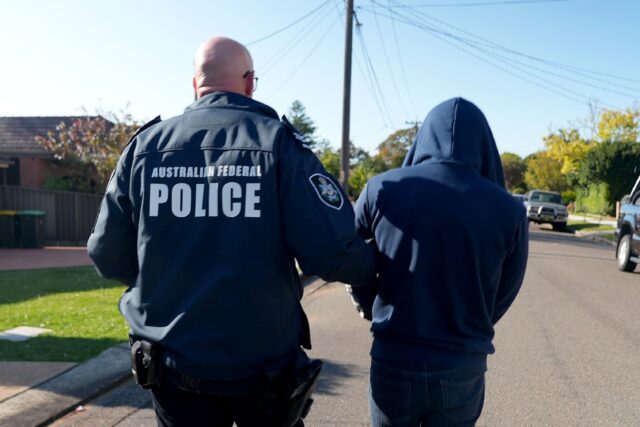 An Australian Federal Police officer arrests a suspect allegedly involved with an encrypte