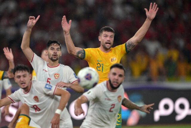 Australia's Cameron Burgess challenges Indonesia's Sandy Walsh (centre L) and Calvin Verdo