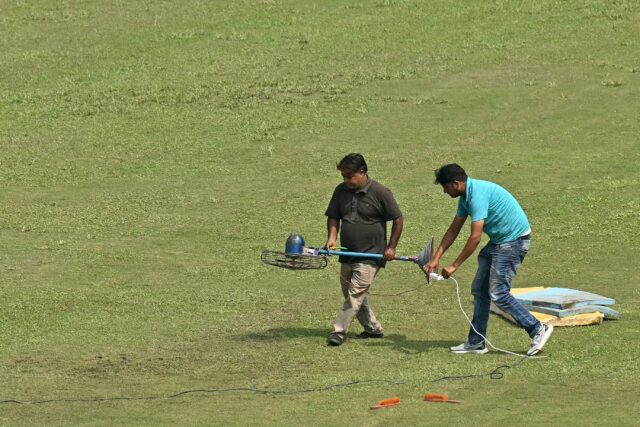 Groundsmen use a fan to dry a patch of wet outfield before the start of the one-off Test c