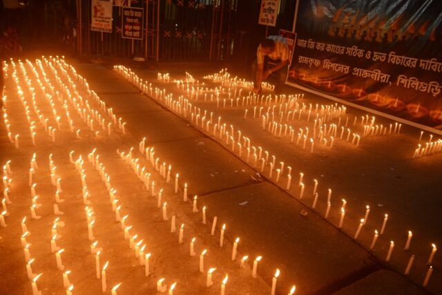 A man lights candles while taking part in protest to condemn the rape and murder of a doct