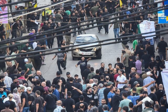 People in Beirut's southern suburbs react after a reported explosion during the funeral of