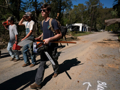 BAT CAVE, NORTH CAROLINA - OCTOBER 2: Men with chainsaws walk along Route 9 in the afterma