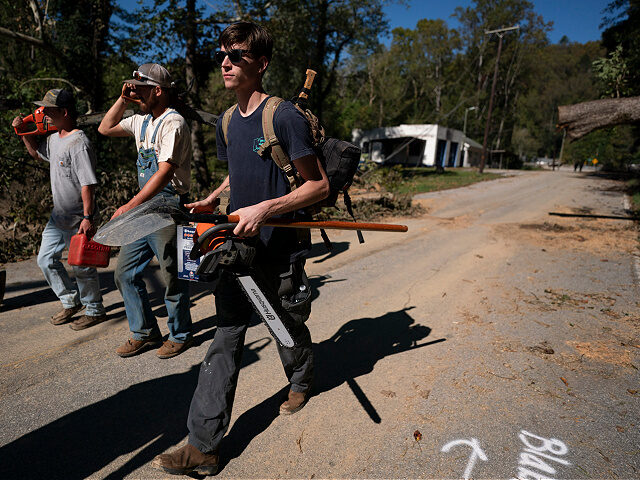 BAT CAVE, NORTH CAROLINA - OCTOBER 2: Men with chainsaws walk along Route 9 in the afterma