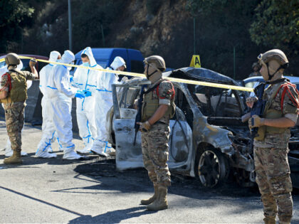 Lebanese army soldiers secure the area as forensic specialists inspect a car targeted in a