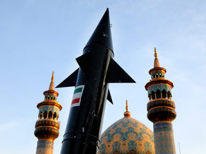 A model of a missile is carried by Iranian demonstrators as minarets and dome of a mosque