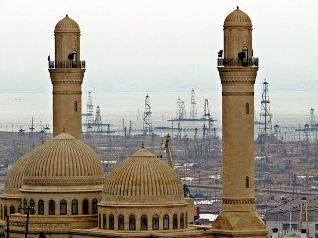 This file photo shows the Bibi Heybat Mosque with oil derricks in the background in Baku,